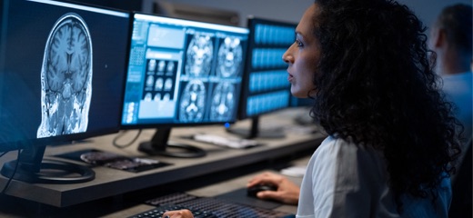 A dark-haired woman in a lab coat looking at brain scans